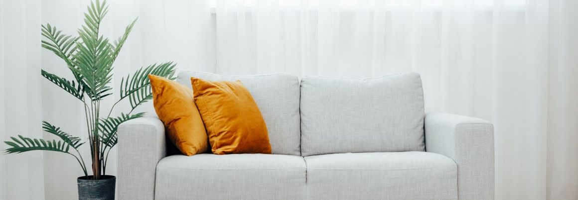 helle Couch mit orangefarbenen Kissen